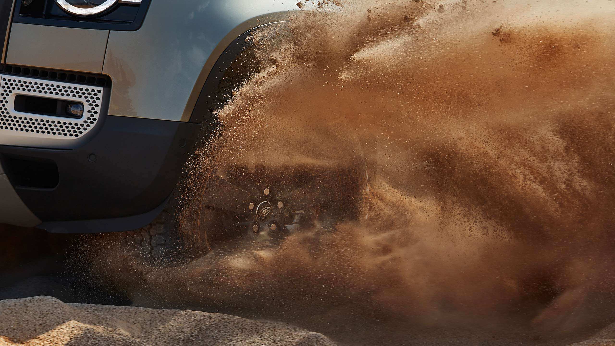 The Defender driving through sandy terrain